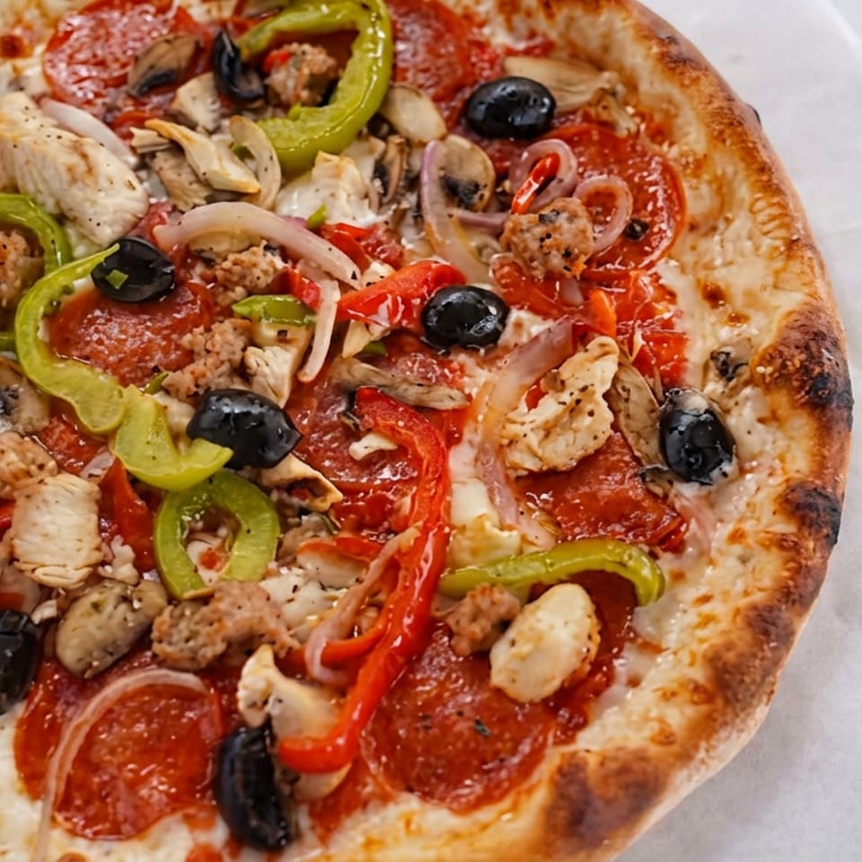 Round pizza topped with pepperoni, sausage, chicken, mushrooms, olives, onions, and green and red peppers.